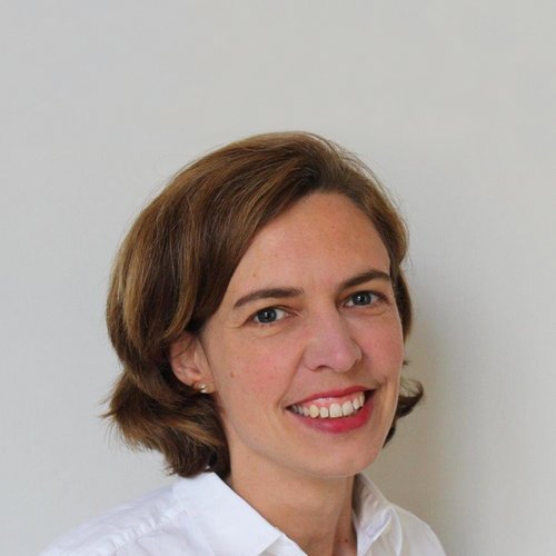 Porträt einer lächelnden Frau mit kurzem braunem Haar und weißem Hemd vor weißem Hintergrund