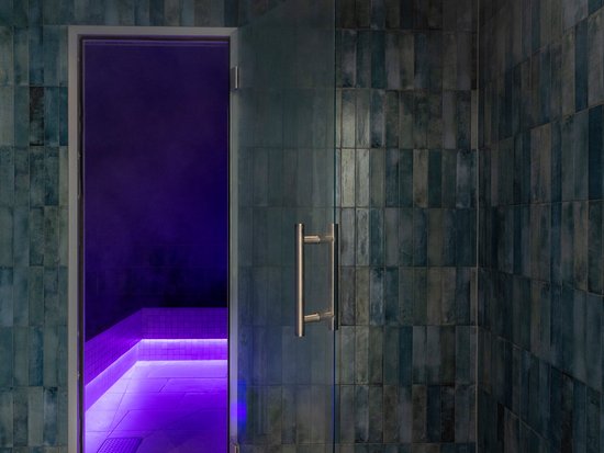 Your spa hotel in Allgäu: Allgäu Sonne Steam room with open glass door and purple LED lighting on light tiles