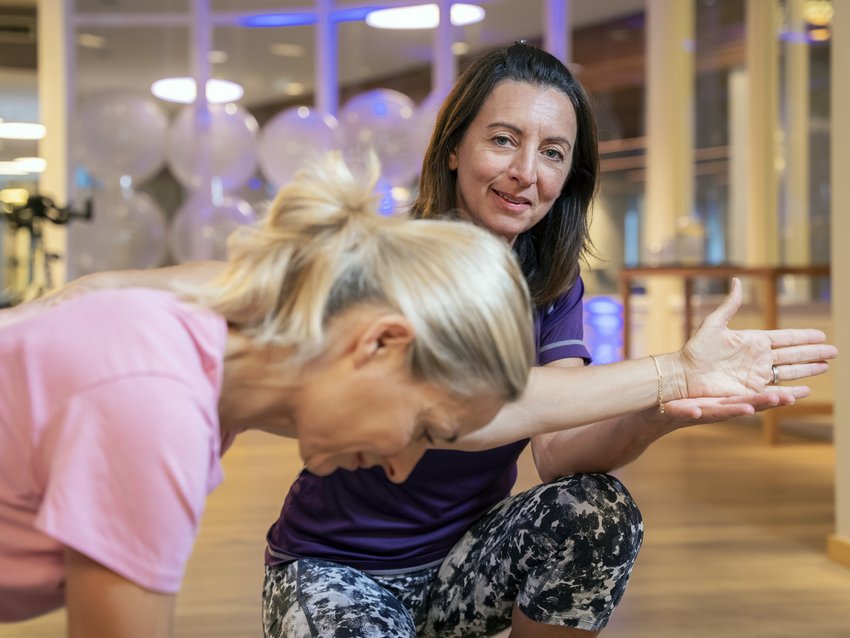 Frauen beim Training im Fitnessstudio, eine zeigt eine Dehnübung