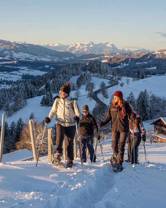 Group snowshoe hiking in snowy mountain landscape at sunset