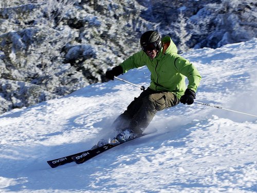 Mann in grüner Jacke beim Skifahren auf verschneiter Piste
