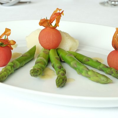 Artfully plated dish with green asparagus and small red vegetable balls